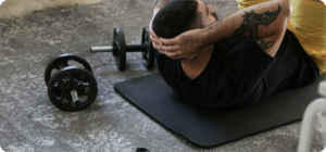 Man sport thuis met gewichten op een matje